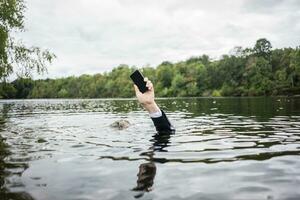 de empresário mão segurando célula telefone dentro uma lago foto