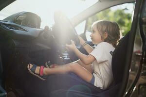 feliz pequeno Garoto sentado em motorista assento dentro uma carro foto