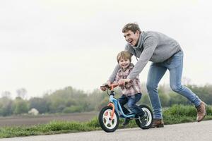 pai ensino dele filho quão para passeio uma bicicleta, ao ar livre foto