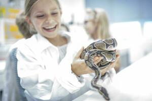 feliz estudante dentro Ciência classe segurando serpente foto
