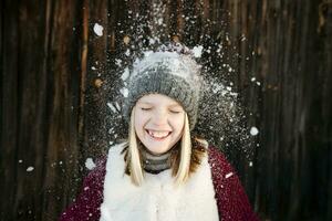 neve queda em feliz menina vestindo lanoso chapéu foto