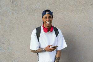 retrato do tatuado jovem homem com Smartphone e vermelho fones de ouvido foto