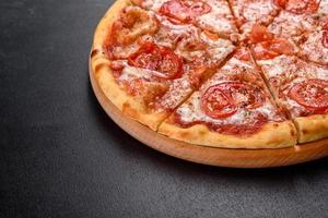 saborosa pizza fresca de forno com tomate, queijo e manjericão em um fundo de concreto foto