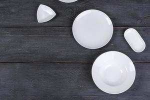 pratos e pires brancos vazios em uma mesa de madeira preta