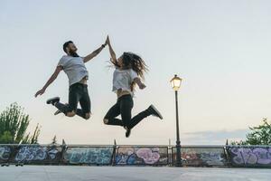 exuberante casal pulando ao ar livre Alto cinco foto