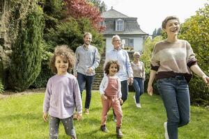 feliz estendido família caminhando dentro jardim do seus casa foto