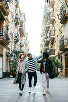 três feliz amigos caminhando dentro a cidade foto