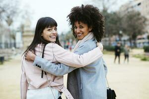 Espanha, barcelona, retrato do dois feliz mulheres dentro cidade parque abraçando girando volta foto