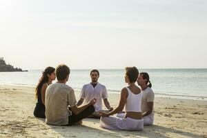 tailândia, koh Fangan, grupo do pessoas meditando juntos em uma de praia foto