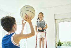 Garoto e menina jogando basquetebol às casa foto
