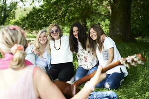 grupo do mulheres com guitarra tendo Diversão às uma piquenique dentro parque foto