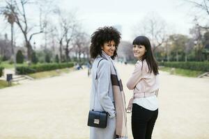 Espanha, barcelona, retrato do dois sorridente mulheres dentro cidade parque girando volta foto