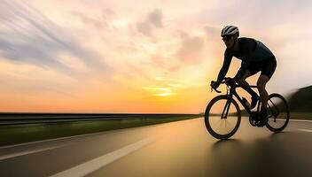 saudável homem equitação bicicleta em a estrada às pôr do sol foto