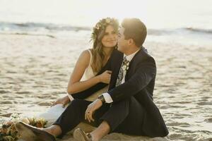 feliz nupcial casal sentado às a de praia foto