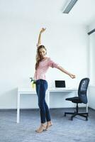 alegre jovem mulher em pé dentro escritório foto
