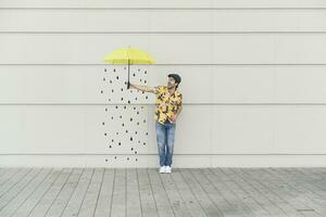 digital composto do jovem homem segurando a guarda-chuva às uma parede com pingos de chuva foto