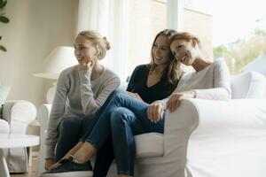 feliz mãe com dois Adolescência meninas em sofá às casa foto