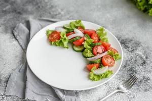 deliciosa salada fresca com vegetais, tomate, pepino, cebola e verduras com azeite de oliva foto