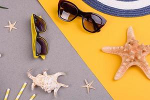 acessórios de praia, óculos e chapéu com conchas e estrelas do mar em um fundo colorido. fundo de verão foto