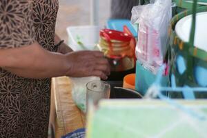 indonésio amanhecer gelo vendedor prepara cliente ordens foto