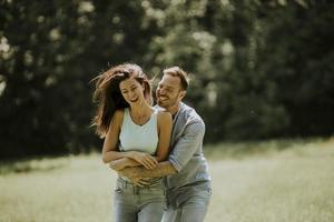 jovem casal afetuoso se divertindo na grama verde foto