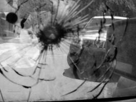 grande rachadura no pára-brisa do carro de um fragmento de bala de atirador militar foto
