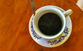 pote de xícara branca azul com mesa de madeira de café preto méxico. foto