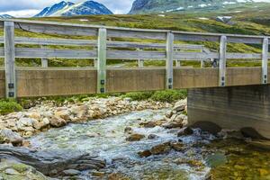 de madeira ponte sobre rio dentro montanhas rondane nacional parque Noruega. foto