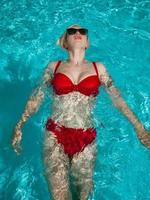 jovem linda garota sexy nadando na piscina privada e relaxando ao sol foto