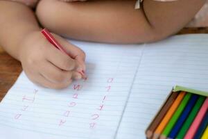 feche a mão da menina com um lápis escrevendo palavras em inglês com a mão foto