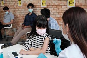 médico injeta uma menina paciente com fila de espera. foto