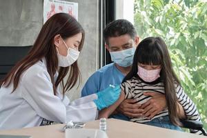 médica vacinando menina asiática na clínica de pediatria. foto