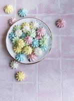 pequenos merengues coloridos no prato de cerâmica foto