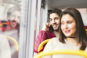 Reino Unido, Londres, retrato do sorridente jovem homem em a telefone dentro uma ônibus foto