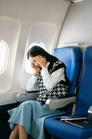 foto do uma frustrado mulher sentado em a avião com dela cabeça dentro dela mãos. ásia mulher sentado dentro uma assento