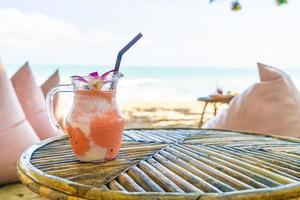 frasco de manga, abacaxi, melancia e iogurte ou smoothies de iogurte com fundo de praia do mar foto