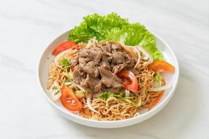 Salada picante de macarrão instantâneo com carne de porco no prato branco - comida asiática foto
