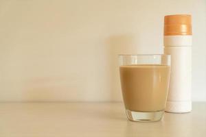 copo de café com leite com garrafas de café prontas para beber na mesa foto