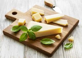 pedaço de queijo parmesão em uma placa de madeira foto