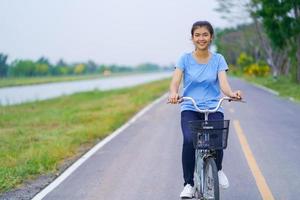 menina com bicicleta, mulher andando de bicicleta na estrada em um parque foto