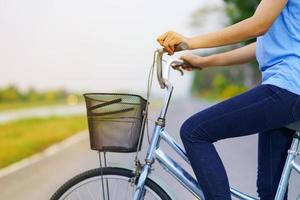 menina com bicicleta, mulher andando de bicicleta na estrada em um parque foto