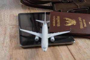 modelo de avião pequeno, passaporte tailandês no fundo da placa de madeira foto