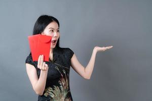 linda mulher asiática usa vestido tradicional chinês com envelope vermelho ou pacote vermelho sobre fundo cinza foto