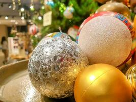 fechar-se e colheita Natal bolas para vender e decorado dentro compras Shopping em embaçado pinho árvore fundo. foto
