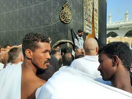 meca, saudita Arábia, agosto 2023 - peregrinos a partir de diferente partes do a mundo fila acima para beijo a Preto pedra às masjid al Haram, meca. foto