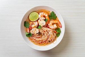 macarrão com sopa picante e camarões em tigela branca - tom yum kung - comida asiática foto