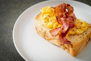 torrada de pão com ovo mexido e bacon em prato branco foto