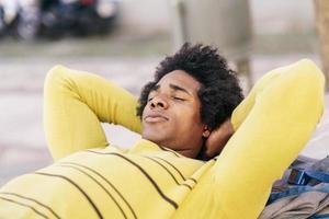 turista negra com cabelo afro deitado no chão ao ar livre.
