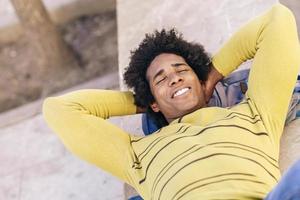 turista negra com cabelo afro deitado no chão ao ar livre.