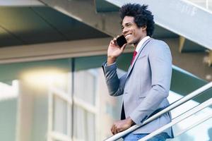 empresário negro usando um smartphone perto de um prédio comercial foto